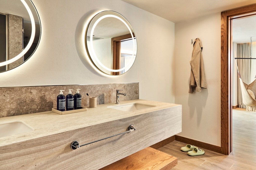 Hallway view of a wardrobe with clothes hanging and a full-length mirror