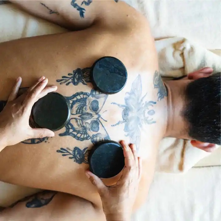map laying on his stomach with spa stones on him