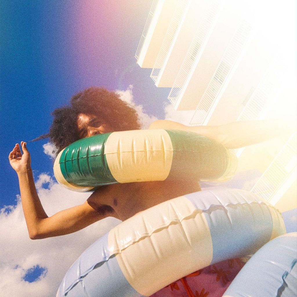 Man having fun by the pool with multiple rubber rings around him